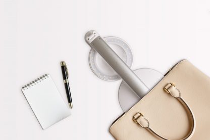 Image of halo go lamp in a handbag with small notepad and pen next to the bag
